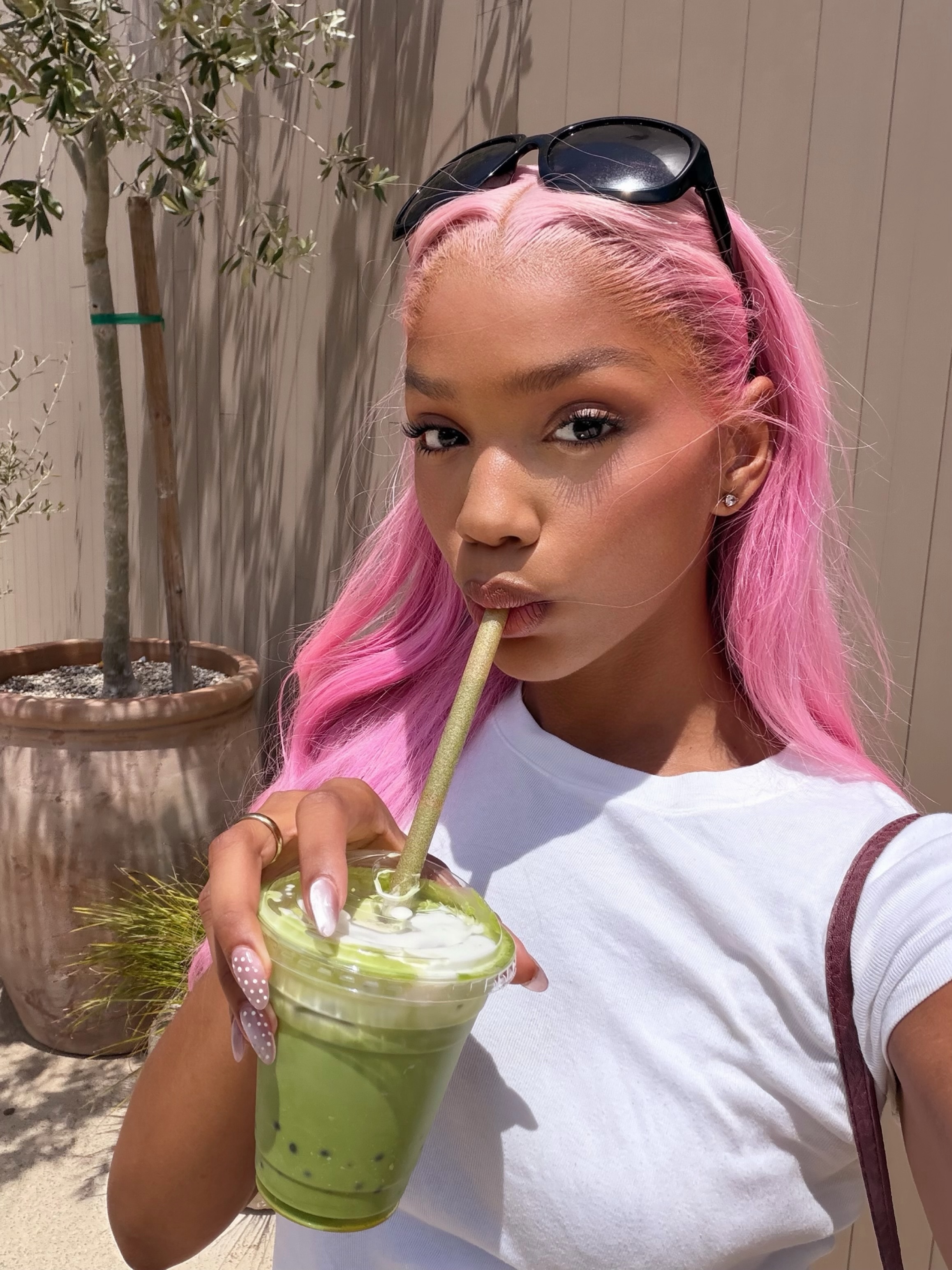 Melanie with pink hair enjoying a matcha drink outdoors